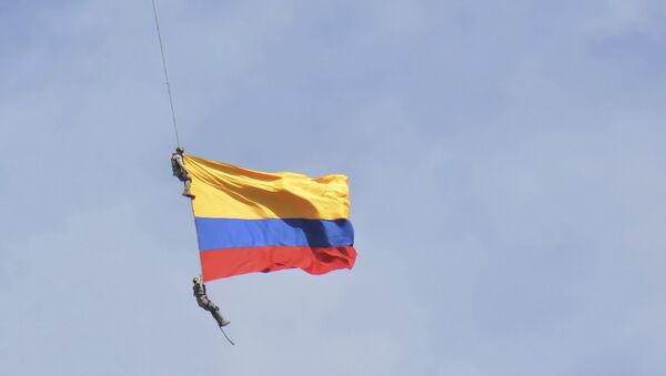 Dos soldados con la bandera de Colombia, colgados de un helicóptero, durante un espectáculo aéreo - Sputnik Mundo