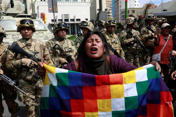 Un manifestante con una bandera de Wiphala frente a miembros de las fuerzas de seguridad durante los enfrentamientos entre partidarios del expresidente boliviano, Evo Morales, y las fuerzas de seguridad en La Paz (Bolivia). - Sputnik Mundo