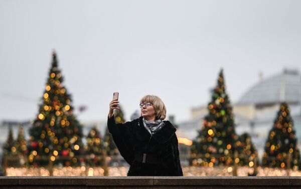 Una mujer se hace una foto con algunos de los 450 árboles decorados de la Plaza del Manege - Sputnik Mundo