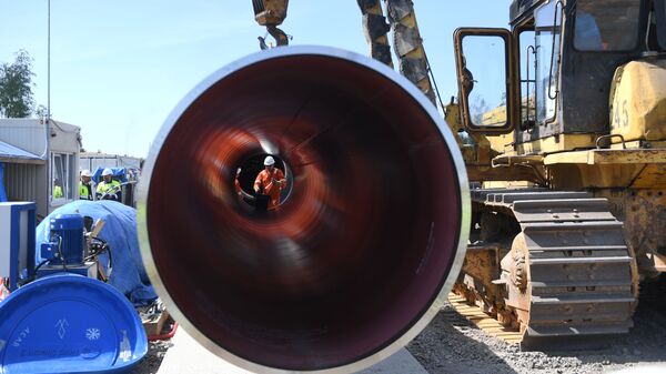 Un trabajador es visto a través de una tubería en el sitio de construcción del gasoducto Nord Stream 2 en Rusia  - Sputnik Mundo