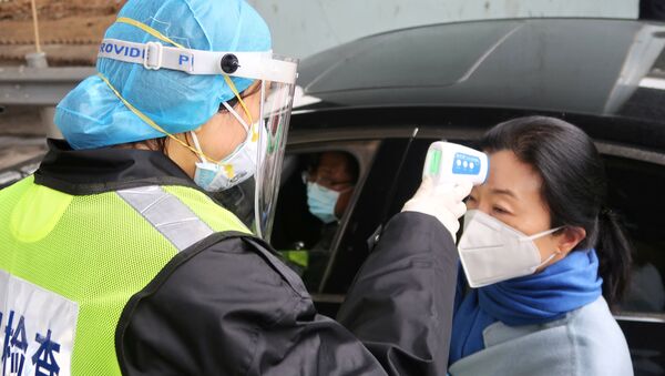 Una oficial de seguridad mide la temperatura de una mujer china - Sputnik Mundo
