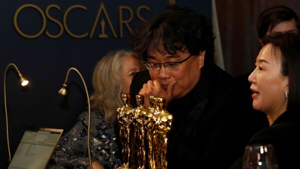 El director surcoreano Bong Joon-Ho mirando las estatuillas ganadas en la ceremonia de los Óscar 2020 - Sputnik Mundo