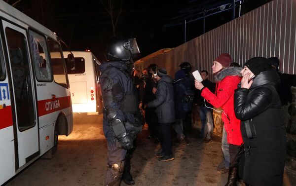Los autobuses que transportan a los evacuados de China pasan por delante de los manifestantes durante una protesta contra su llegada - Sputnik Mundo
