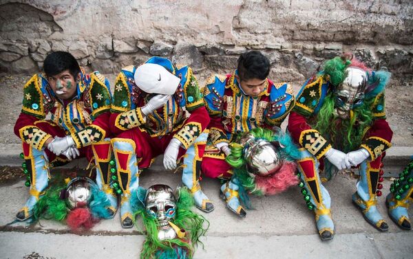 Jóvenes con trajes típicos de Carnaval tomando un descanso en una acera. - Sputnik Mundo