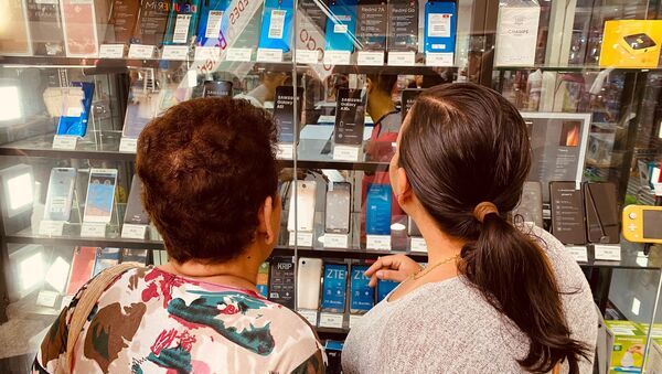 Dos mujeres miran un expositor de celulares en una tienda de Caracas - Sputnik Mundo