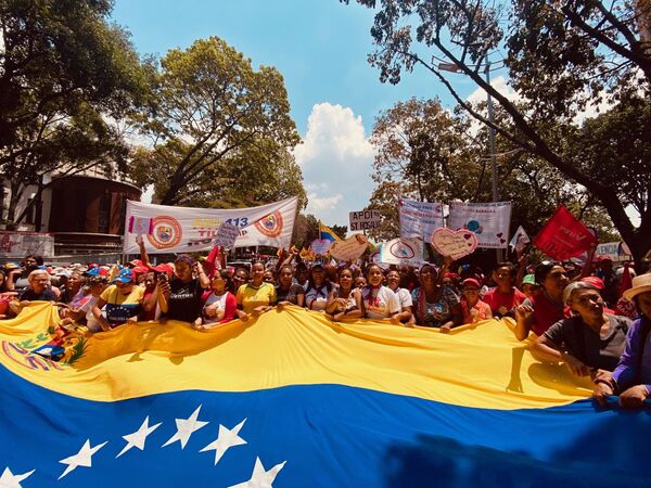 Un grupo de mujeres que participan en la multitudinaria marcha por el Dia de la Mujer en Caracas portan una bandera gigante de Venezuela mientras avanzan caminando por la avenida Universidad en direccion al Panteon Nacional, punto final de la manifestacion. Las mujeres van cantando consignas revolucionarias y en pro de los derechos de la mujer en el mundo. - Sputnik Mundo