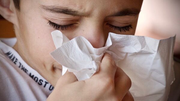Un niño estornudando y con un pañuelo. Imagen referencial - Sputnik Mundo