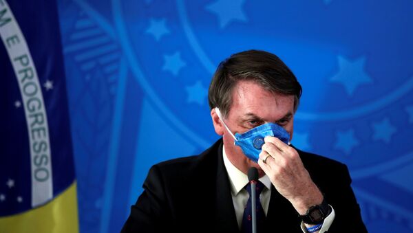 El presidente de Brasil Jair Bolsonaro acomodando una mascarilla - Sputnik Mundo