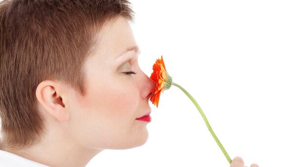 Una mujer huele una una flor - Sputnik Mundo