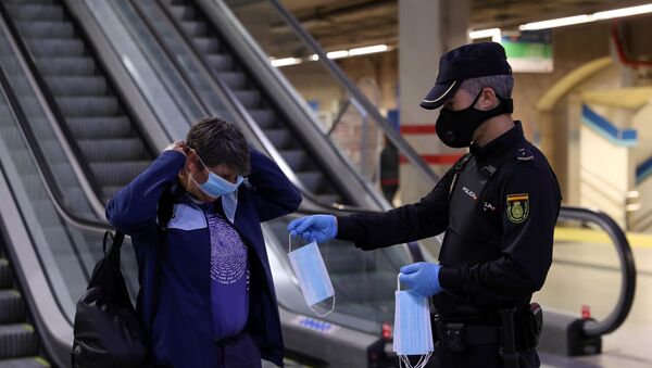 Un policía entrega una mascarilla a una mujer en el metro de Madrid - Sputnik Mundo