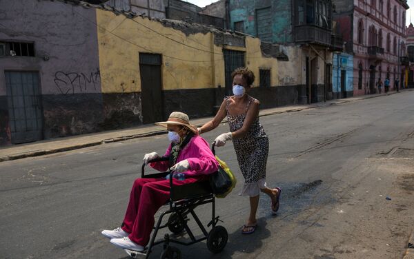 Flor Vaso empuja a su madre Carmen Reyes, de 84 años, en una silla de ruedas después de que fue vacuna contra la Influenca, durante el estado de emergencia decretado por el gobierno. Lima, Perú.  - Sputnik Mundo
