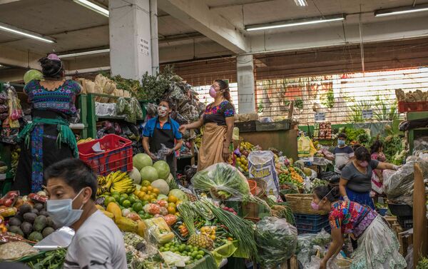 Vendedores protegidos con tapabocas organizando la mercadería en un mercado de frutas local. Ciudad de Guatemala, Guatemala. - Sputnik Mundo