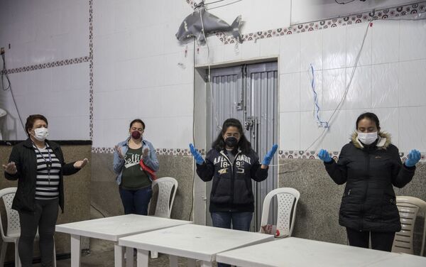 Un grupo de mujeres, distanciadas entre sí, rezan antes de recibir folletos de alimentos del grupo católico Amigos Misión Colombia. Bogotá, Colombia.  - Sputnik Mundo