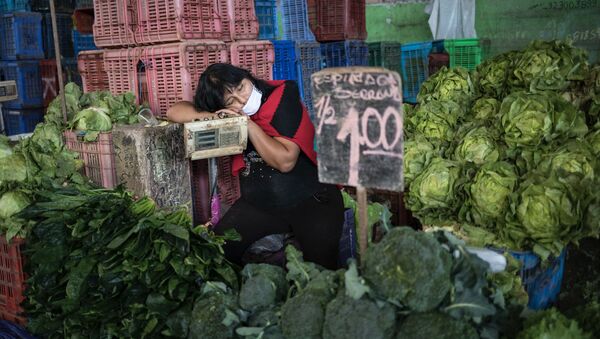 Kathy Velázquez, usando una mascarilla protectora como precaución contra el coronavirus, toma una siesta en su puesto de verduras mientras espera a los clientes en Lima. - Sputnik Mundo