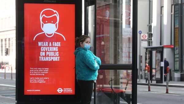 Una chica con mascarilla en una parada de autobús en Londres, Reino Unido - Sputnik Mundo