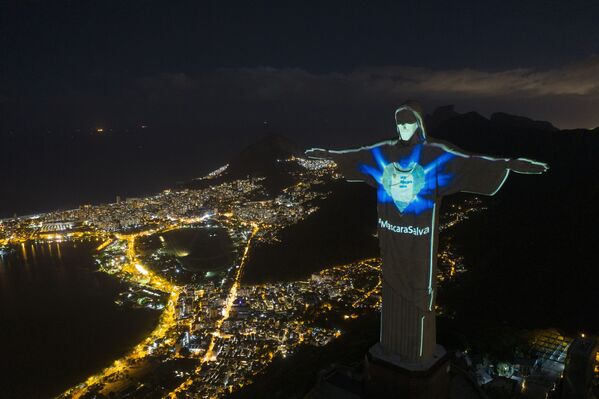 Estatua de Cristo Redentor con iluminación en forma de máscara y con una inscripción en portugués que reza 'La máscara salva' en Río de Janeiro, Brasil. - Sputnik Mundo