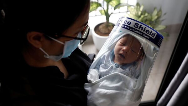 Un recién nacido protegido por una máscara protectora contra el coronavirus - Sputnik Mundo