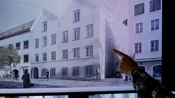 Un hombre apunta a una pantalla de televisión que muestra el plan elegido para un rediseño arquitectónico de la casa en la que nació Adolf Hitler. - Sputnik Mundo