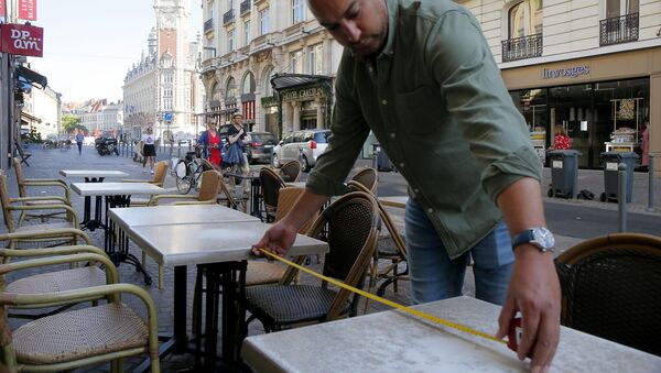 Un hombre toma medidas para asegurar el distanciamiento físico en un bar - Sputnik Mundo