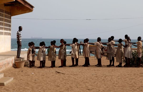 Ученики стоят в ряд во дворе своей школы, поврежденной штормами и береговой эрозией, в Багиде, Того - Sputnik Mundo