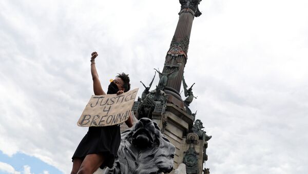 Un manifestante cerca de una estatua de Cristóbal Colón en Barcelona, España - Sputnik Mundo