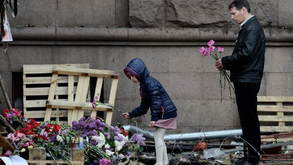 Una niña y un hombre ponen flores en memoria de los quemados en la Casa de los Sindicatos de Odesa - Sputnik Mundo
