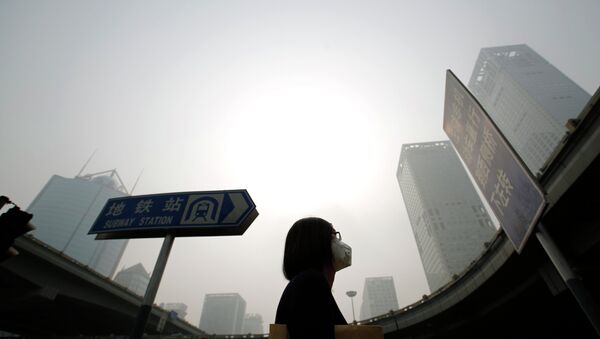A woman wearing a mask makes her way on a street amid heavy haze and smog in Beijing, in this October 11, 2014 - Sputnik Mundo
